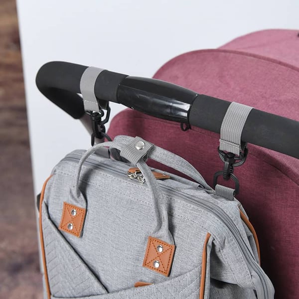 A grey backpack with a pink handle attached to it.